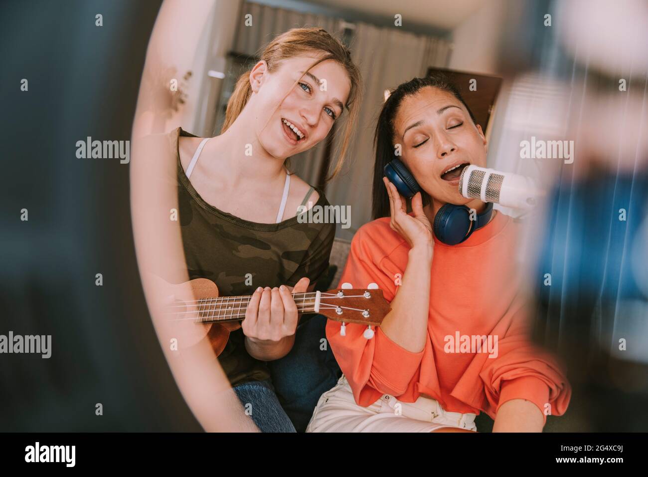 Girl playing ukulele while woman singing on microphone at home Stock Photo Alamy