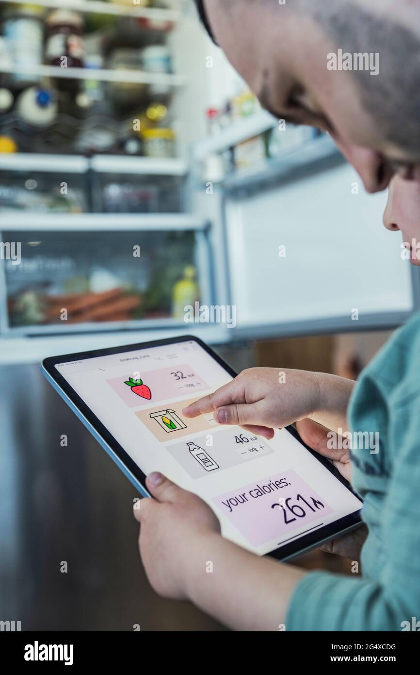 Son and father using digital tablet in kitchen at home Stock Photo