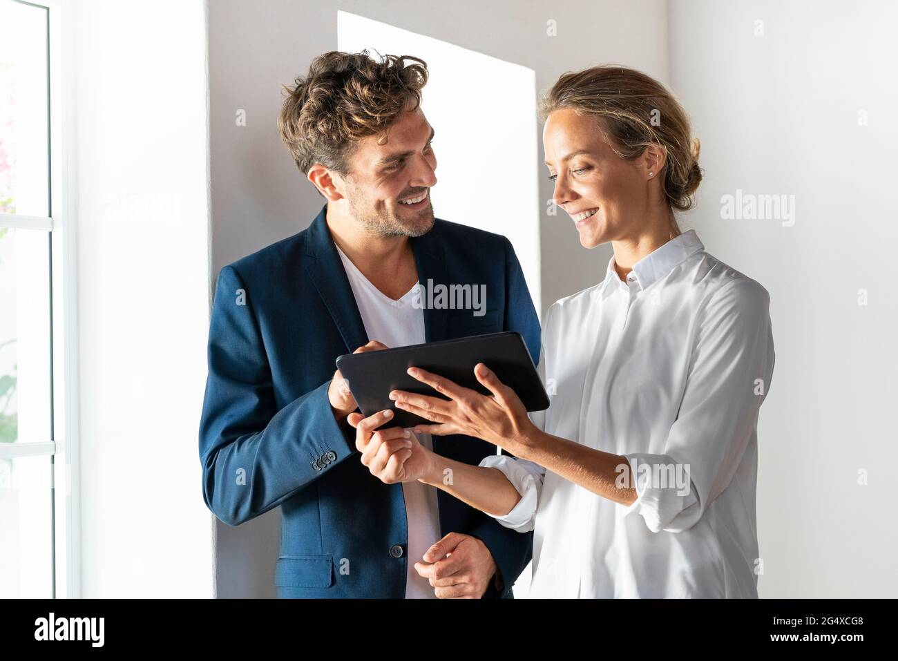 Smiling colleagues using digital tablet while working at office Stock Photo
