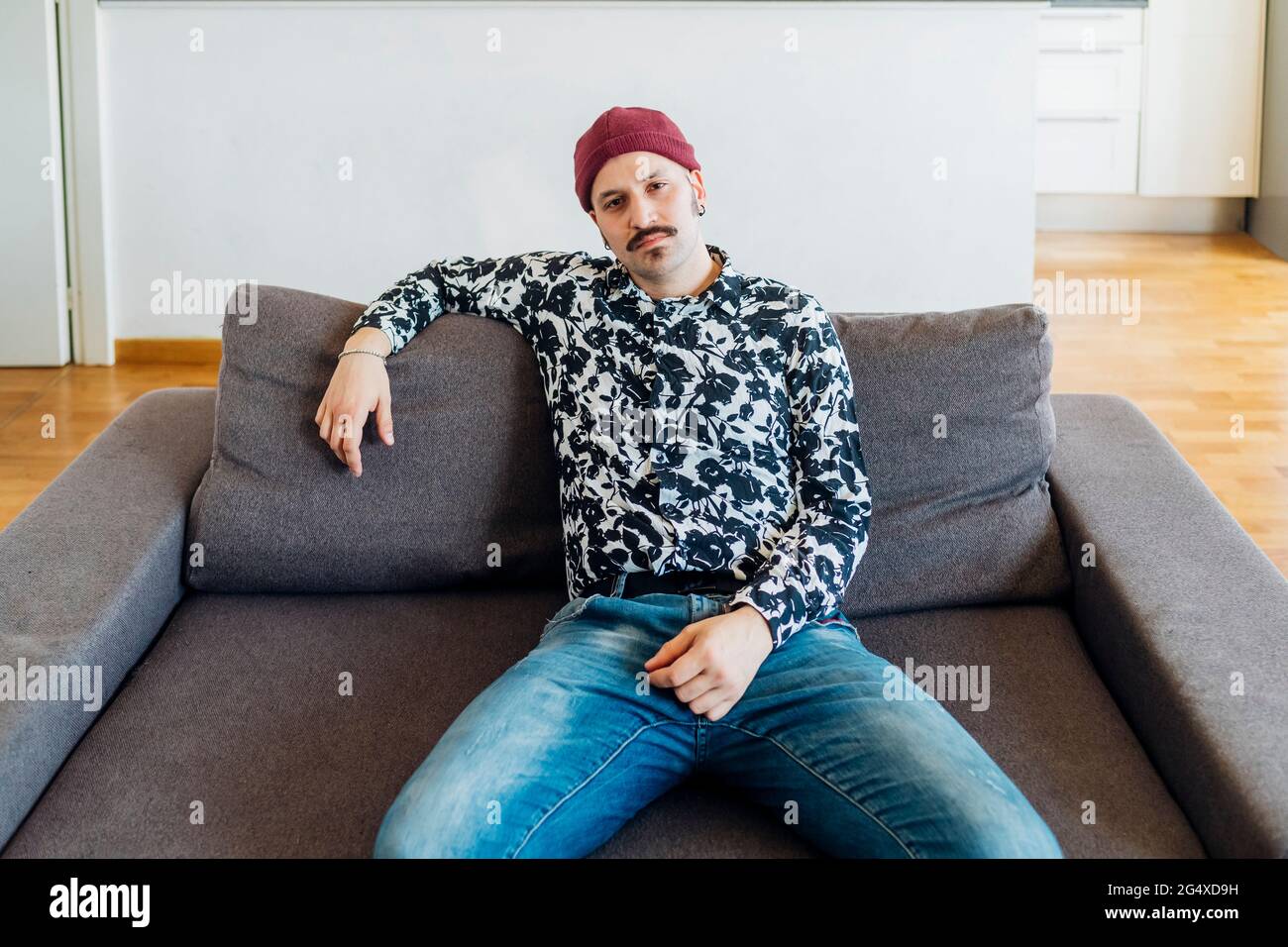 Young man sitting on sofa at home Stock Photo