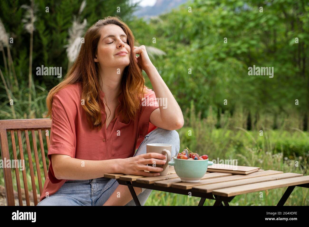 Beautiful woman sitting with eyes closed on chair in garden Stock Photo ...