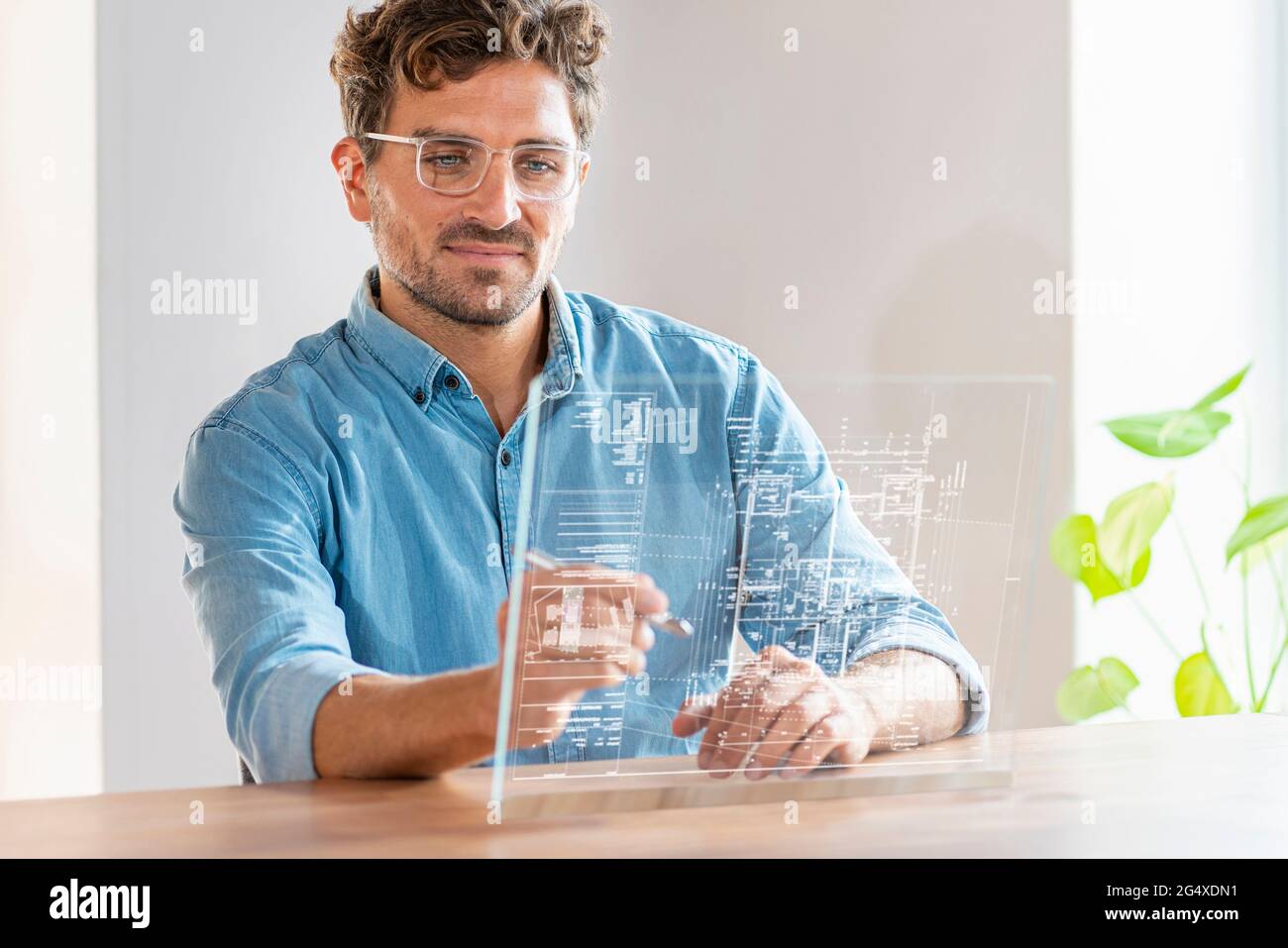 Male architect using futuristic digital tablet while working in office Stock Photo