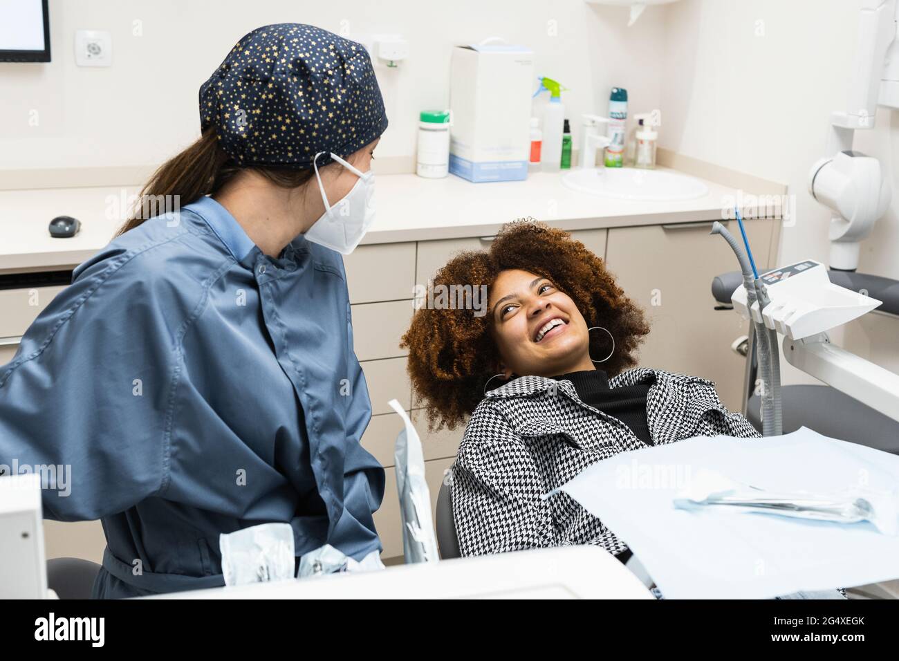 Afro female patient smiling at dentist wearing protective face mask in