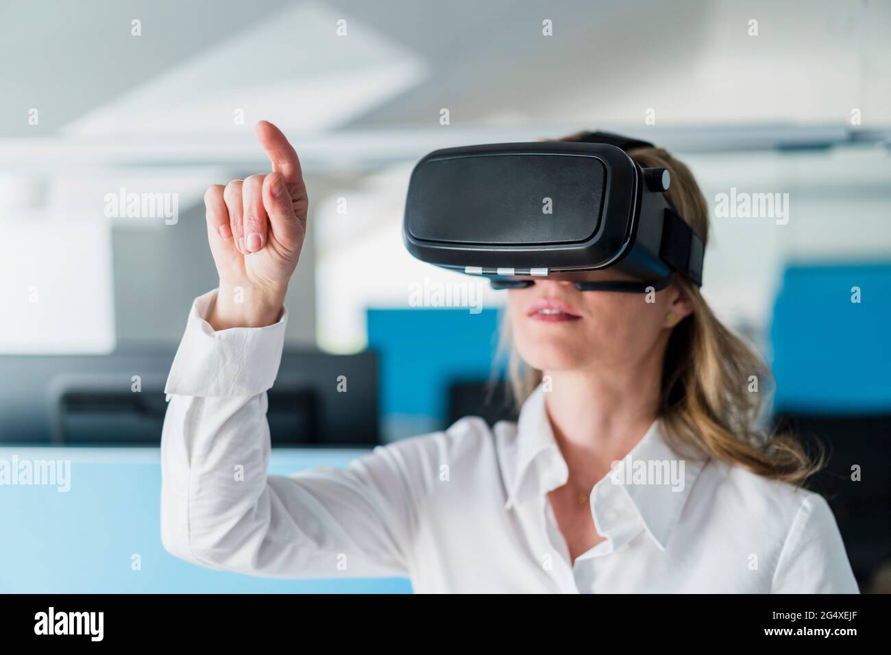 Businesswoman gesturing while using virtual reality headset in office Stock Photo