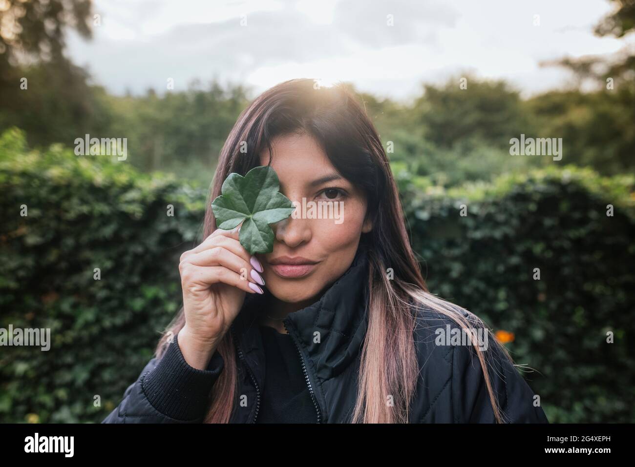 Woman holding leaf in front of eye Stock Photo - Alamy
