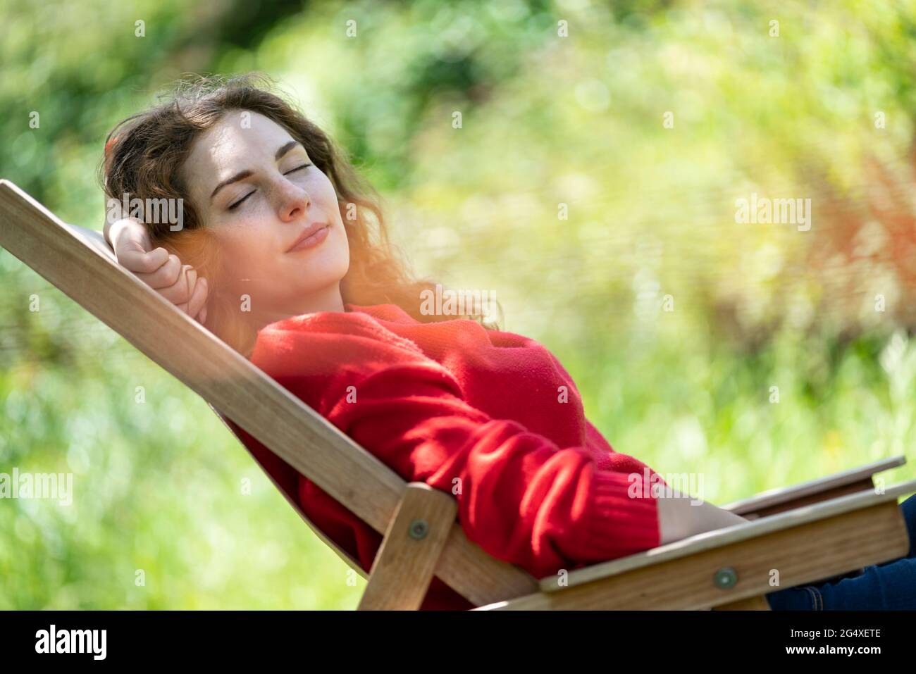 Woman with eyes closed relaxing on chair in garden Stock Photo - Alamy