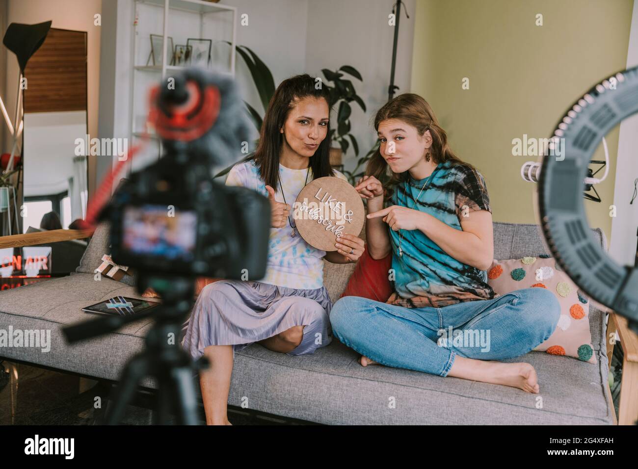 Women showing like and subscribe sign while vlogging at home Stock Photo