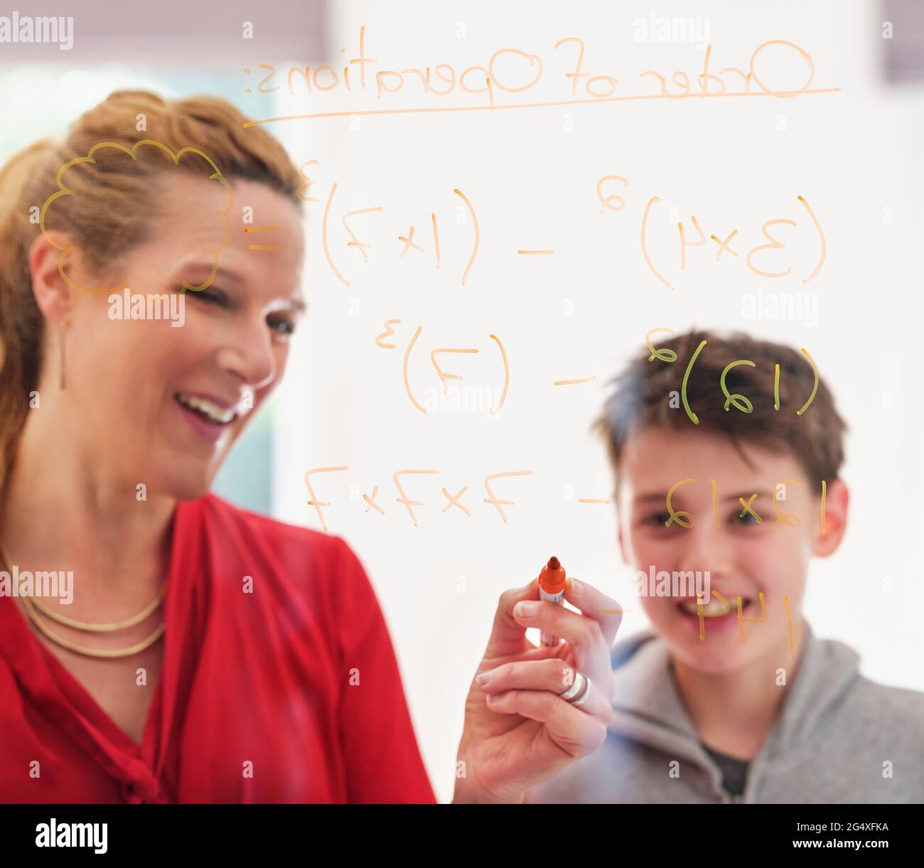 Mother teaching son while writing on glass Stock Photo