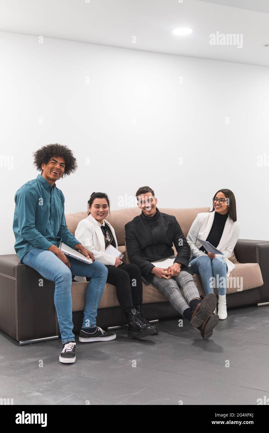Cheerful male and female professional sitting on sofa at office Stock Photo