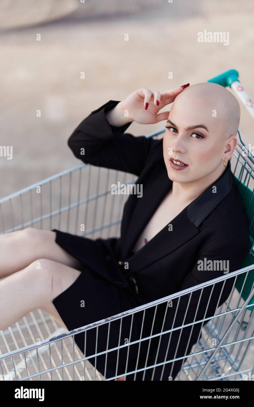 Bald transgender woman sitting in shopping cart Stock Photo