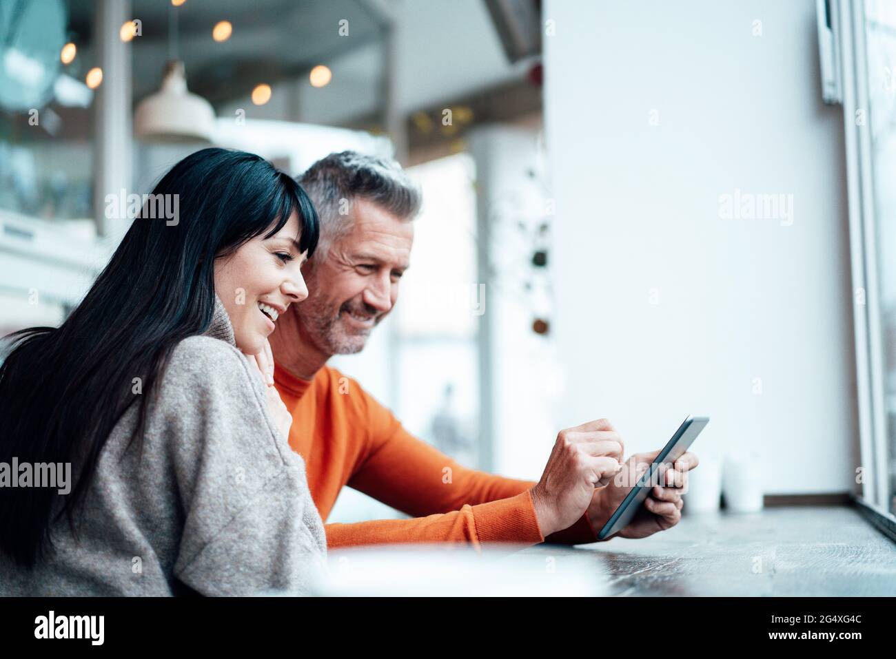 Smiling mature couple using smart phone at cafe Stock Photo