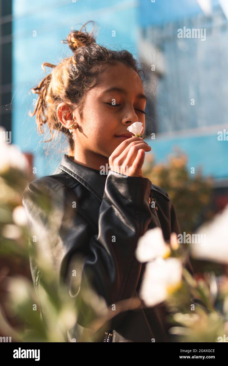 Girl in leather jacket smelling white flower Stock Photo