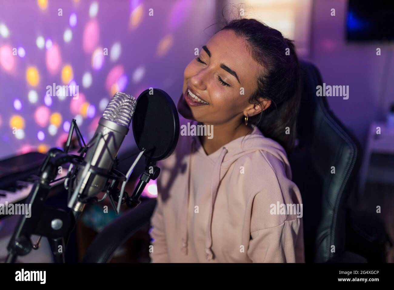 Female singer with eyes closed singing in studio Stock Photo