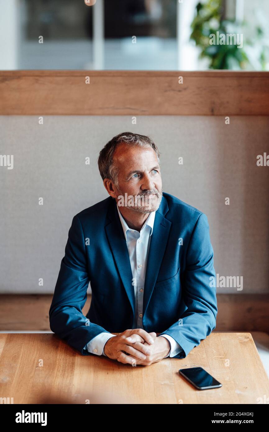 Thoughtful businessman looking away while sitting at office Stock Photo
