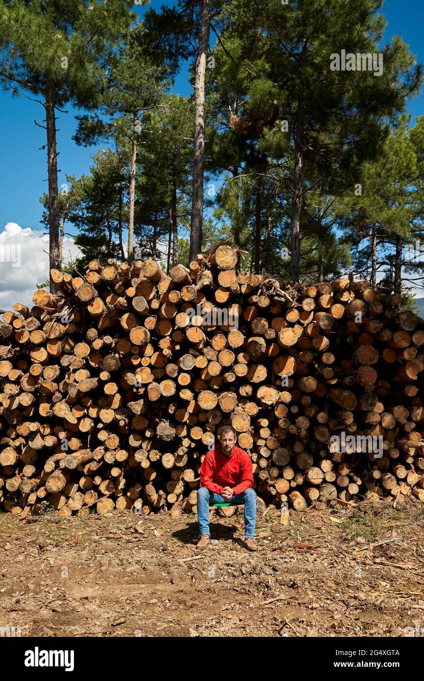 Lumberjack sitting in front of tree trunks at lumber industry Stock Photo
