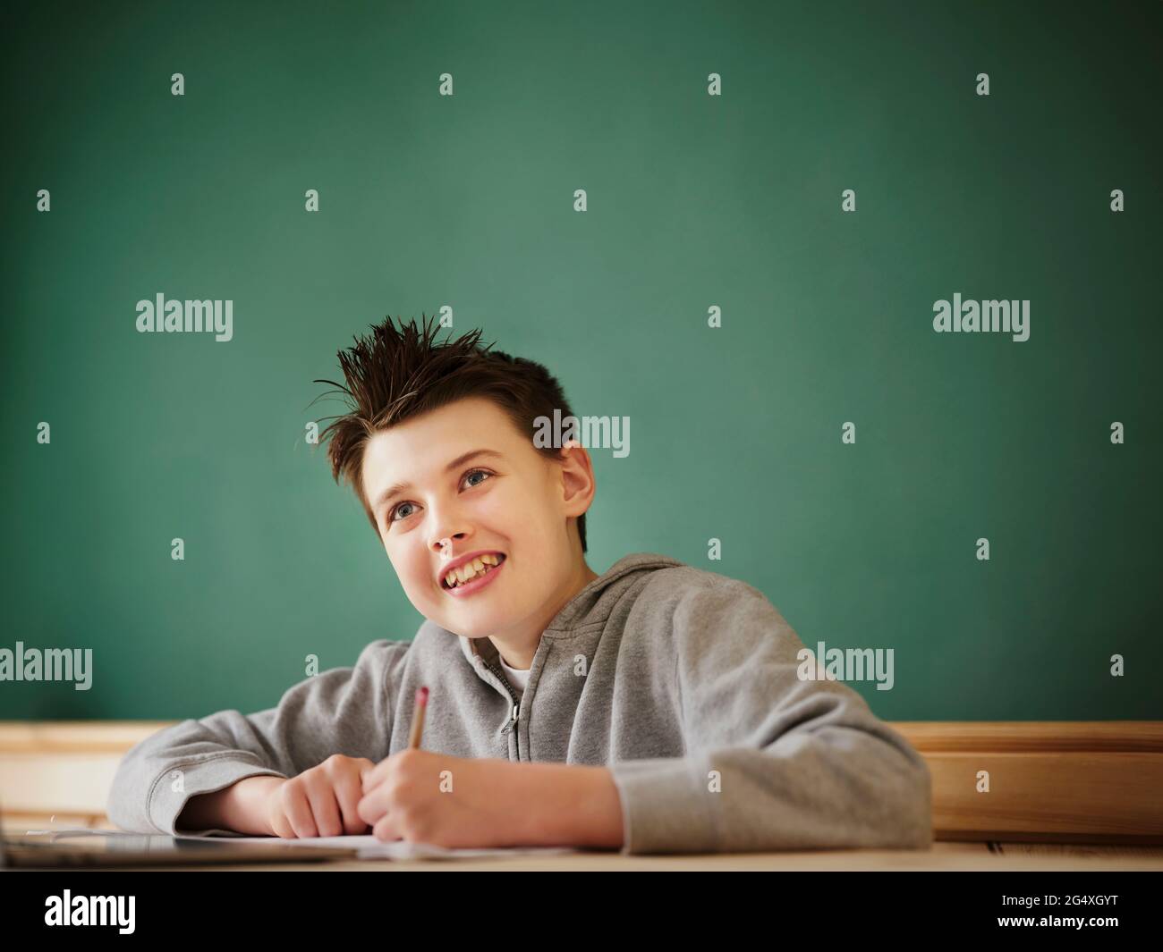 Smiling boy looking away while studying at home Stock Photo