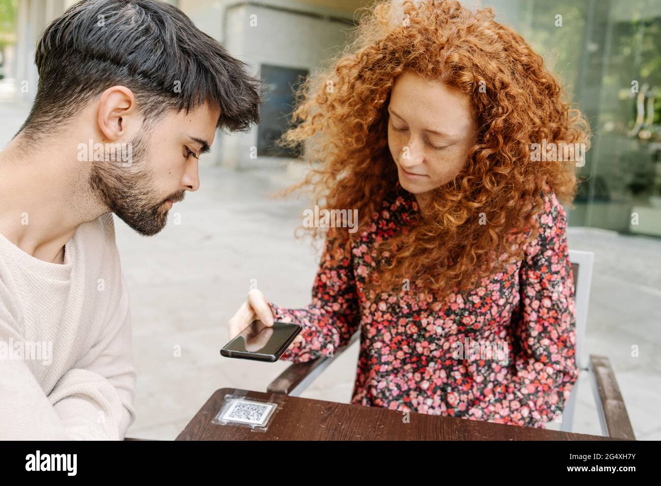 Woman scanning QR code on table in cafe Stock Photo