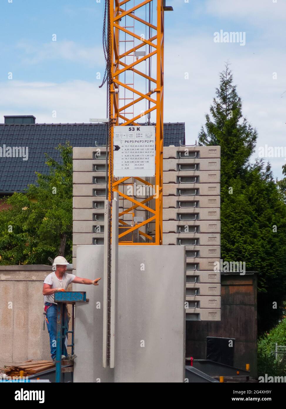 a construction worker in front of a crane supporting the lifting of a prefabricated component Stock Photo