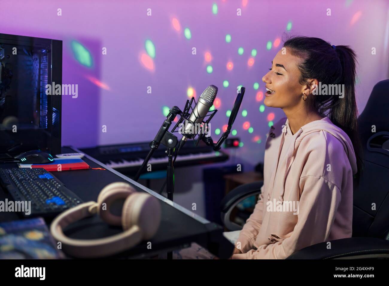 Young female singer singing in studio Stock Photo