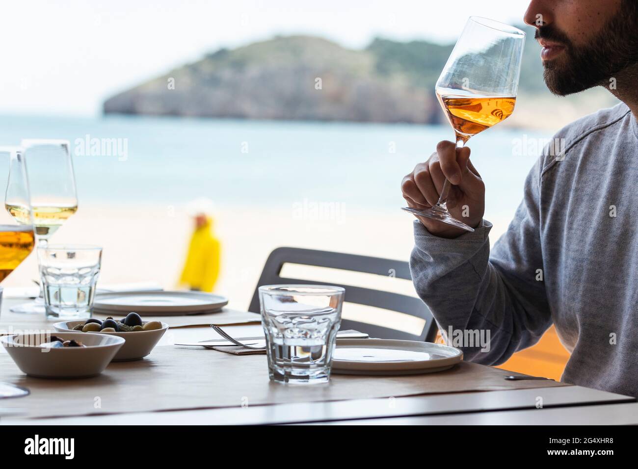 Young man drinking wine at beach restaurant Stock Photo - Alamy