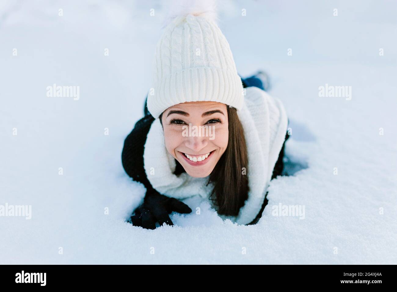 Happy woman in knit hat lying on snow Stock Photo