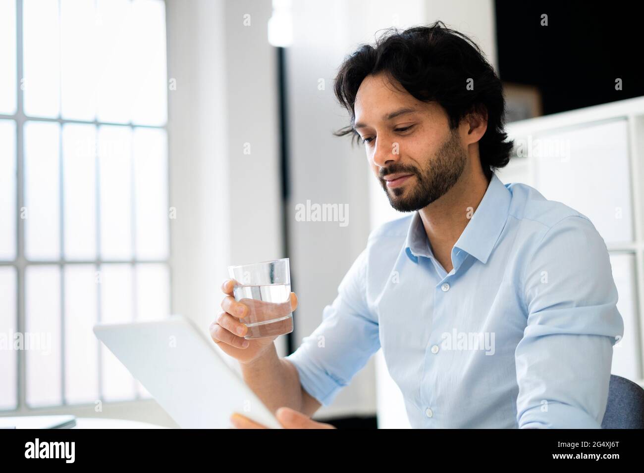 Businessman with drinking glass using digital tablet in office Stock Photo