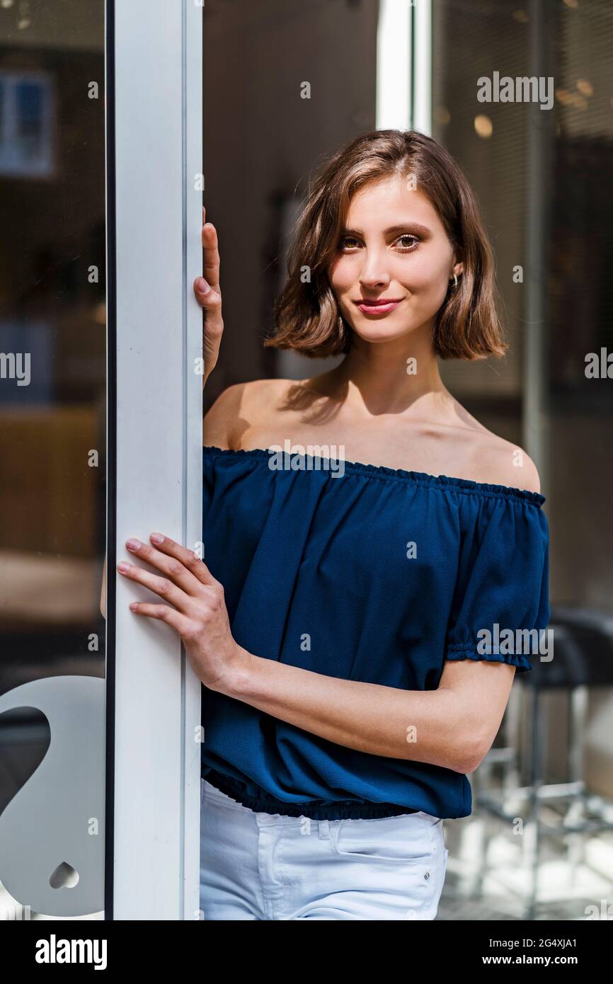 Smiling female entrepreneur with medium length hair standing at doorway Stock Photo