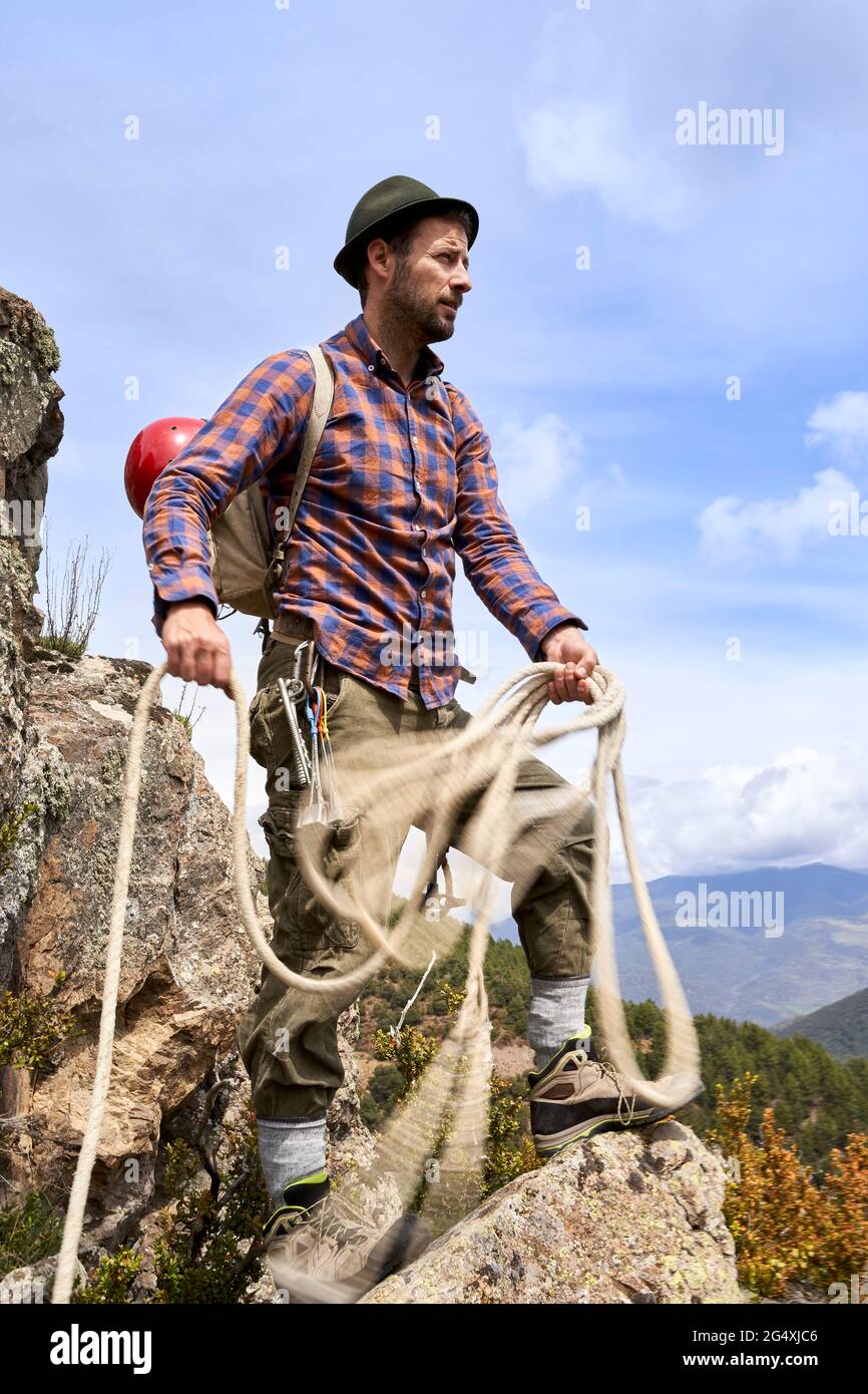 Mountaineer holding rope while standing on rock Stock Photo