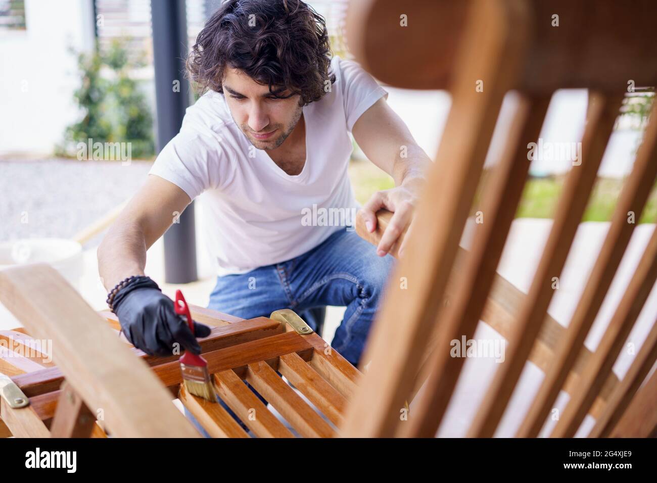 Mid adult man painting wooden deck chair Stock Photo