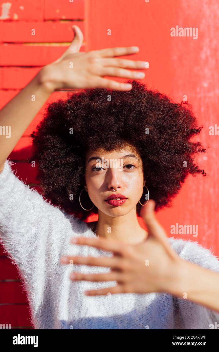 Afro hair woman gesturing in front of wall Stock Photo - Alamy