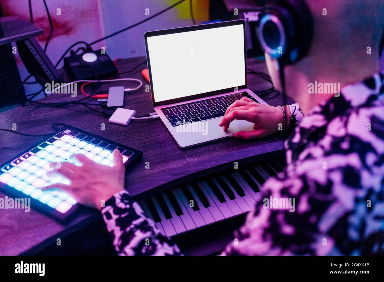Male composer wearing headphones using laptop and digital tablet in studio Stock Photo