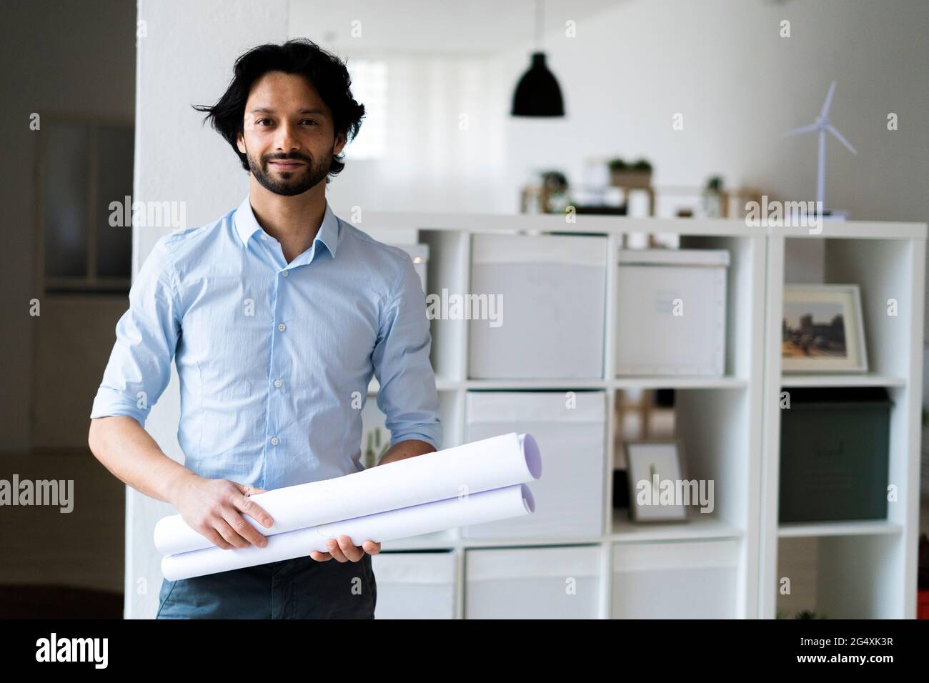 Young male entrepreneur holding document while standing in office Stock Photo