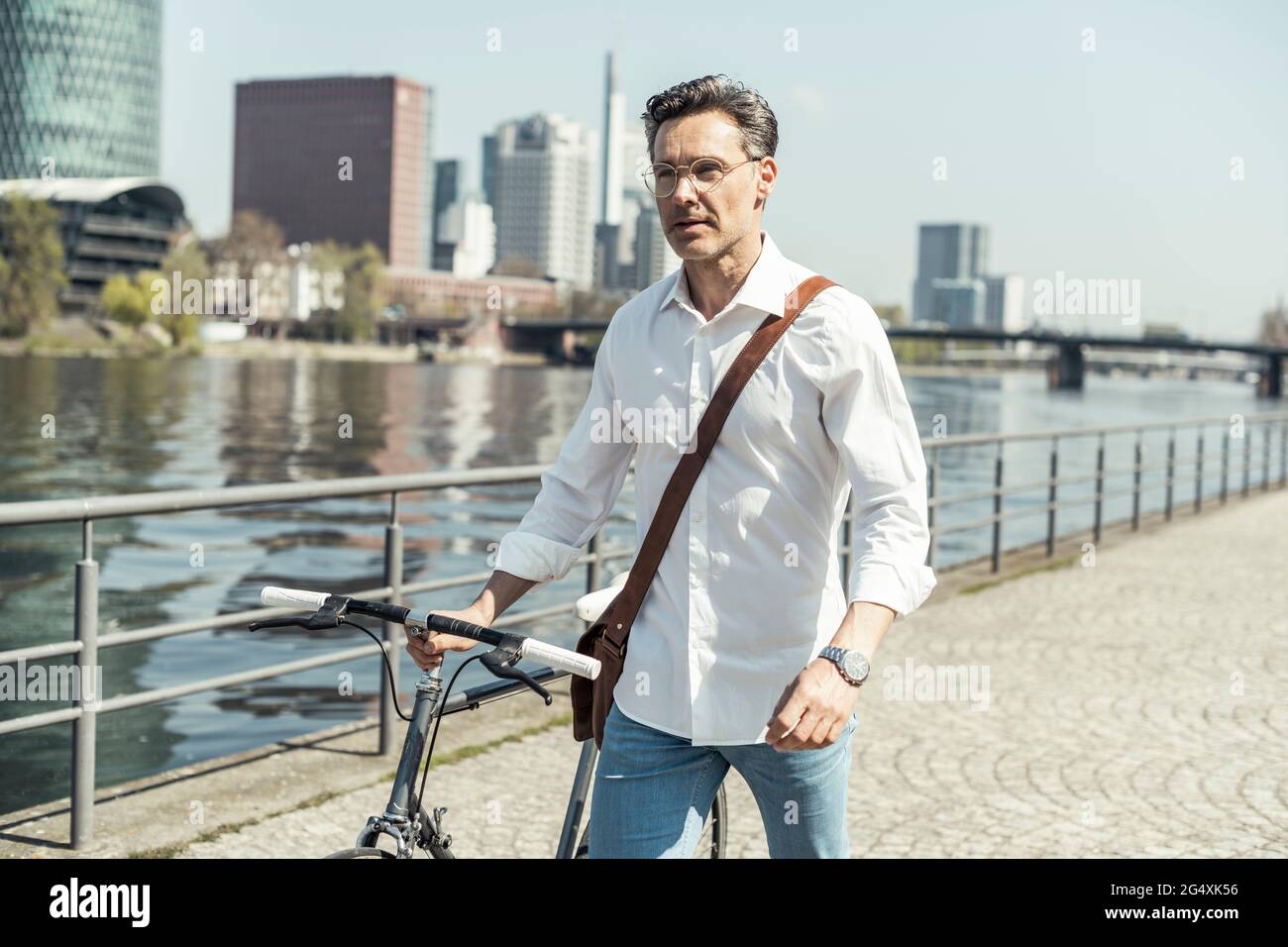 Businessman walking with bicycle in city Stock Photo