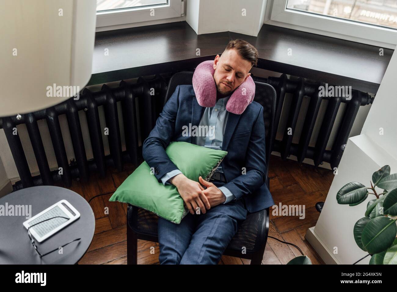 Mid adult male entrepreneur with neck pillow resting in office Stock Photo