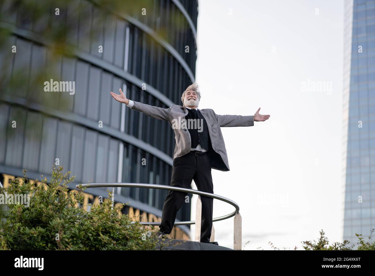 Ecstatic businessman with arms outstretched standing in front of office ...