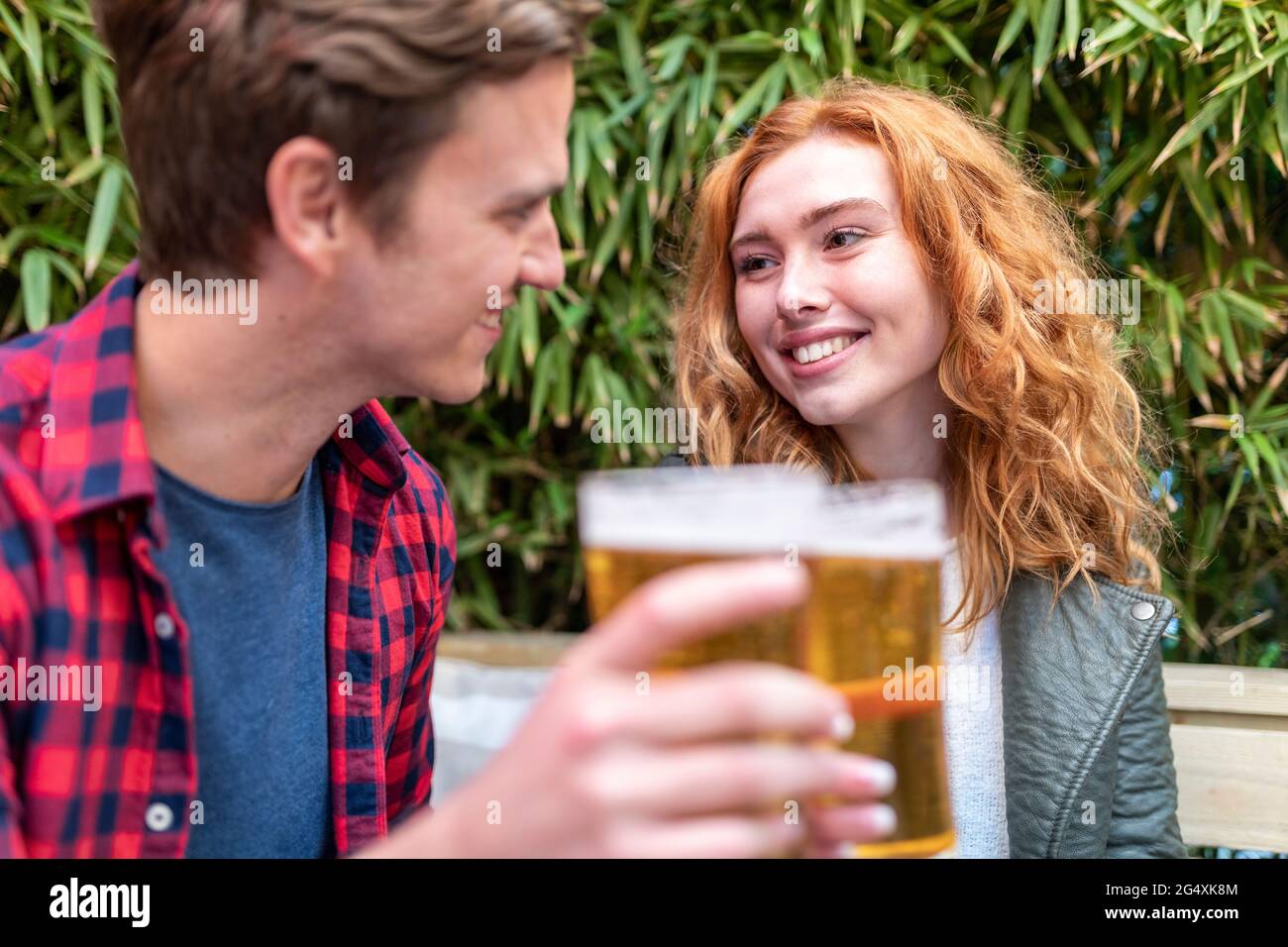 Smiling woman looking at boyfriend holding beer glass at pub Stock Photo