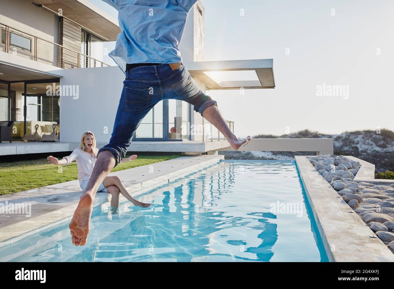 Happy woman looking at man jumping in swimming pool Stock Photo