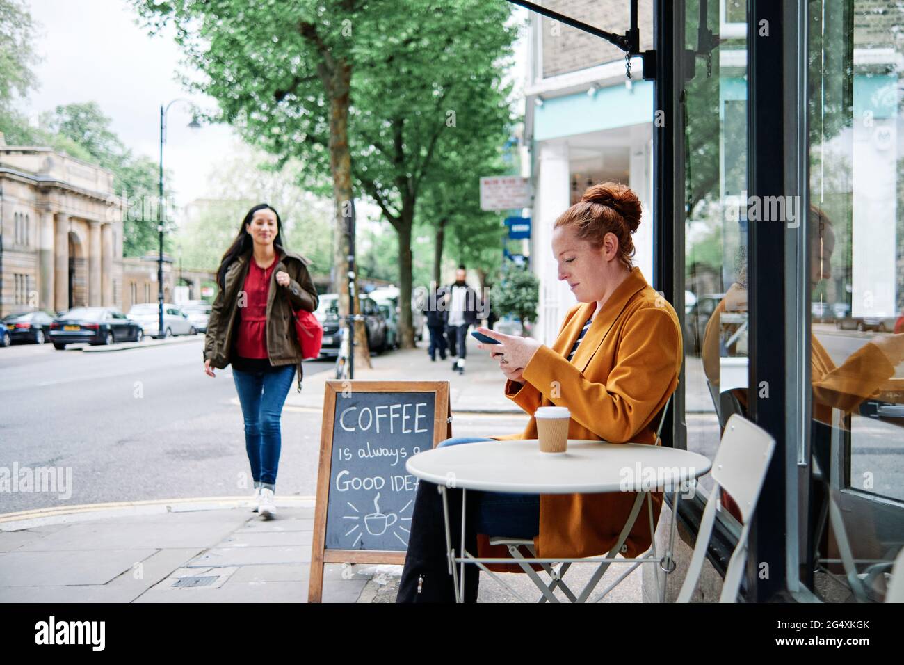 Woman using mobile phone at sidewalk cafe Stock Photo