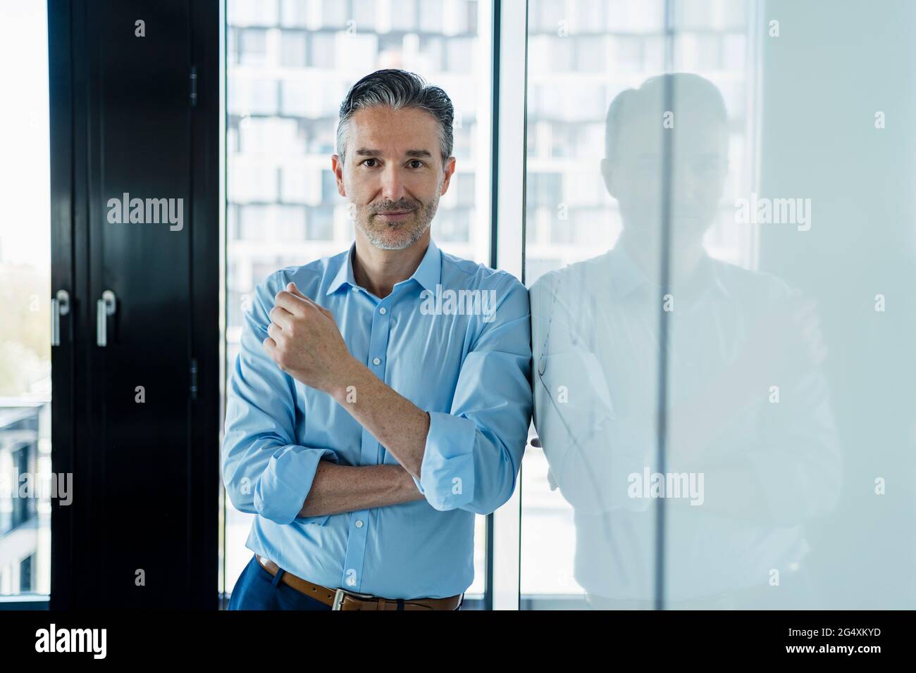 Male entrepreneur leaning on white board while standing in office Stock Photo
