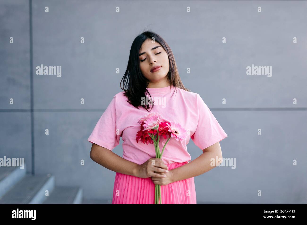 Woman with eyes closed holding bunch of pink flowers by steps Stock ...
