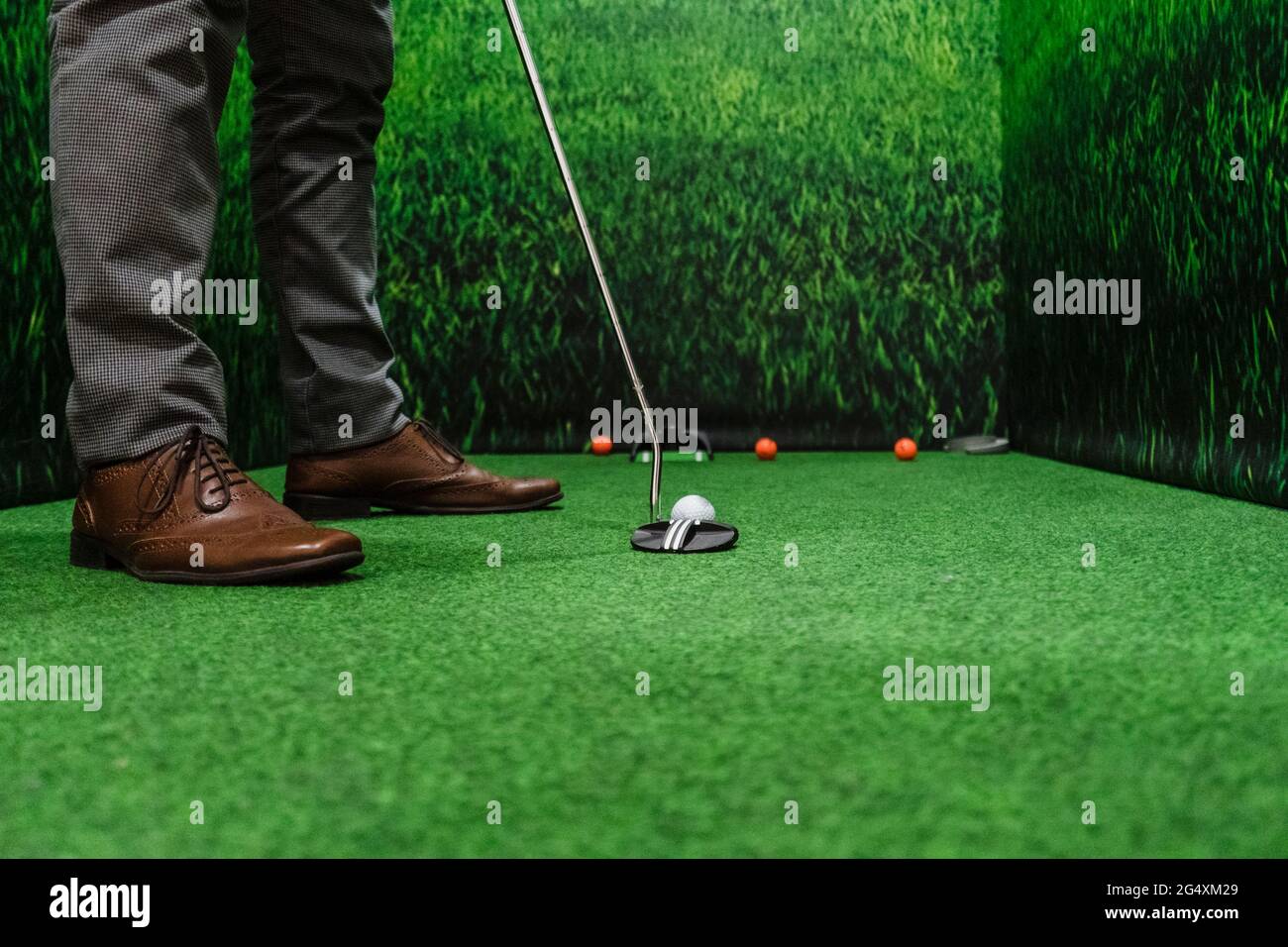 Businessman playing golf on green course at office Stock Photo