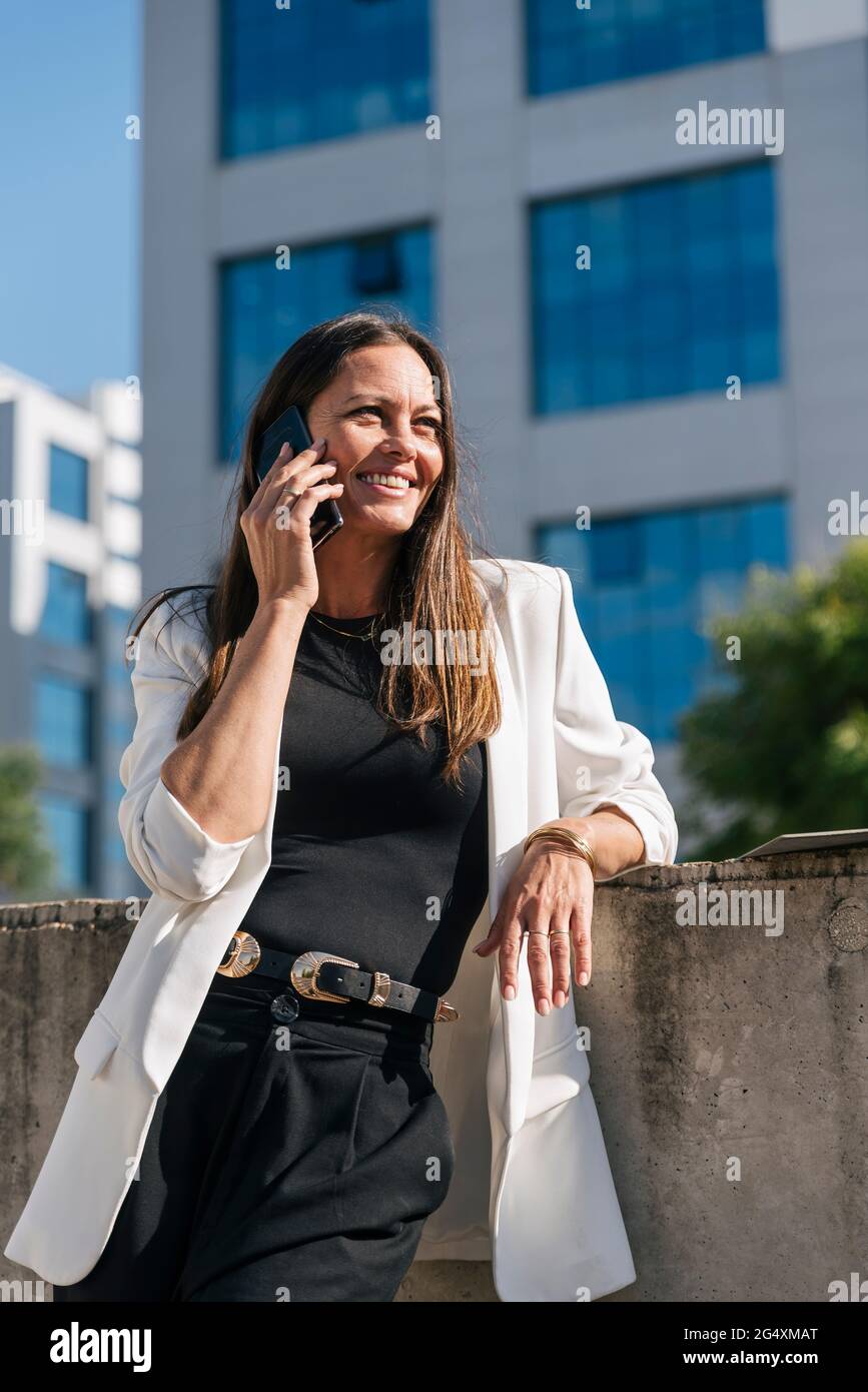 Female entrepreneur smiling while talking on mobile phone Stock Photo