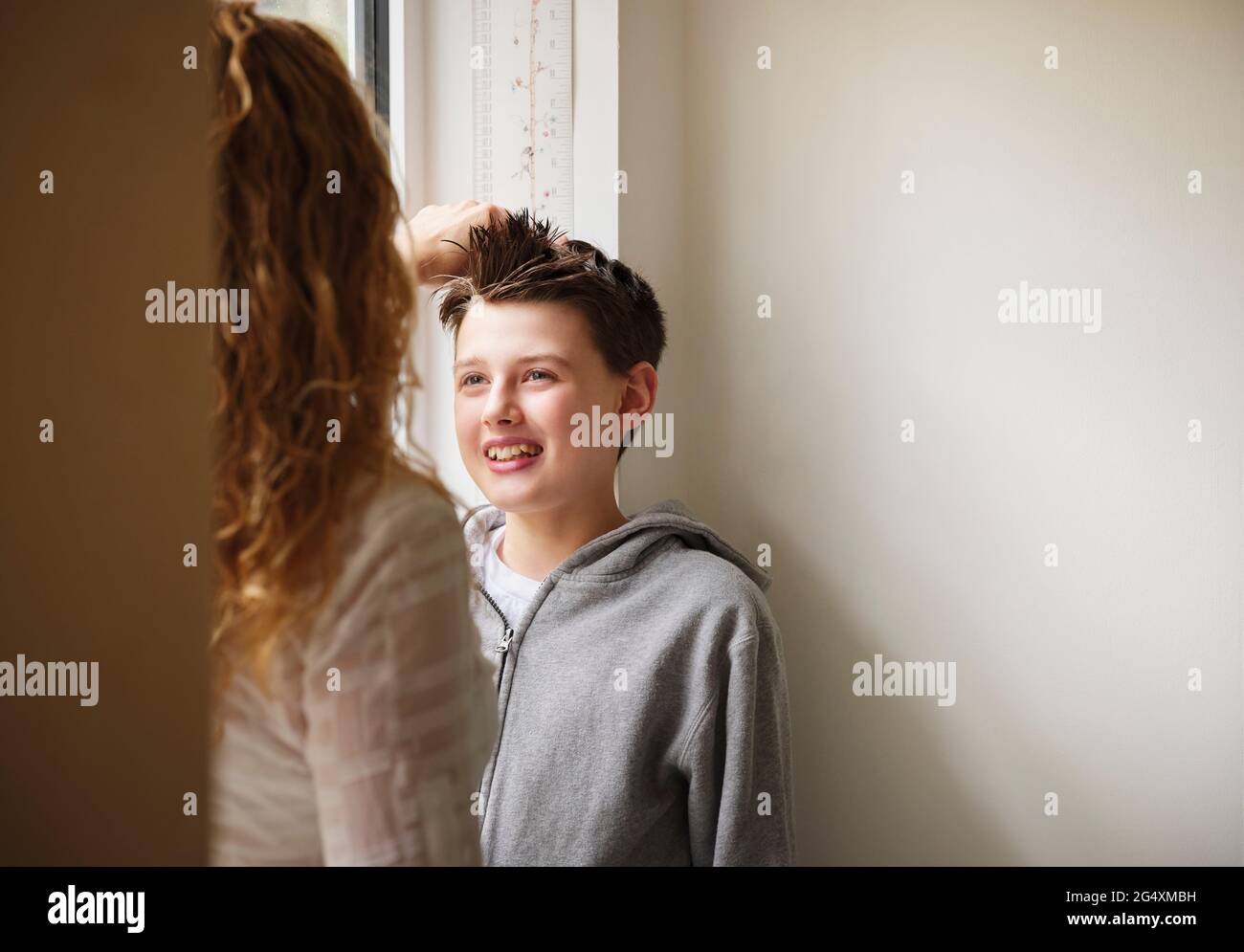 Mother measuring height of son at home Stock Photo