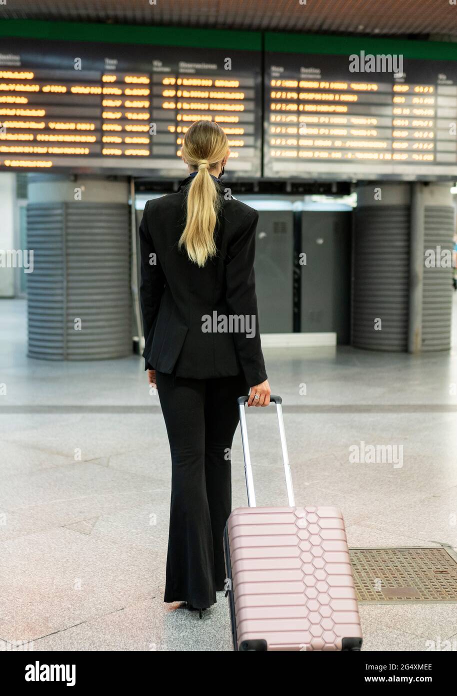 Female flight attendant walking with suitcase at airport Stock Photo