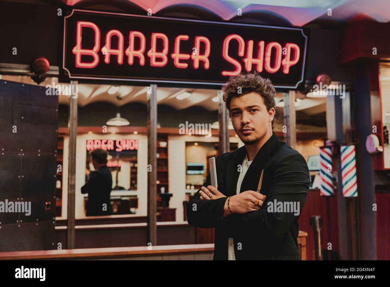 Male hairdresser with scissor and comb standing outside barber shop Stock Photo