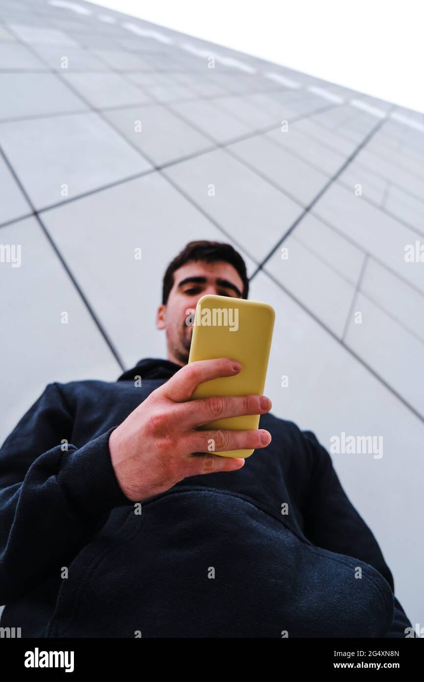 Man using smart phone by wall Stock Photo