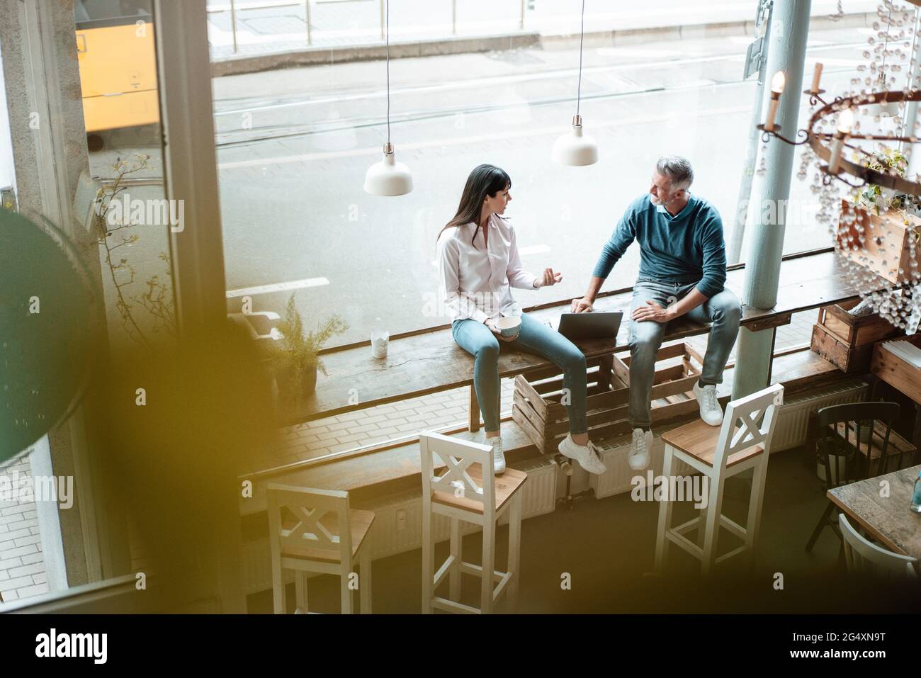 Team working together while sitting by window at cafe Stock Photo