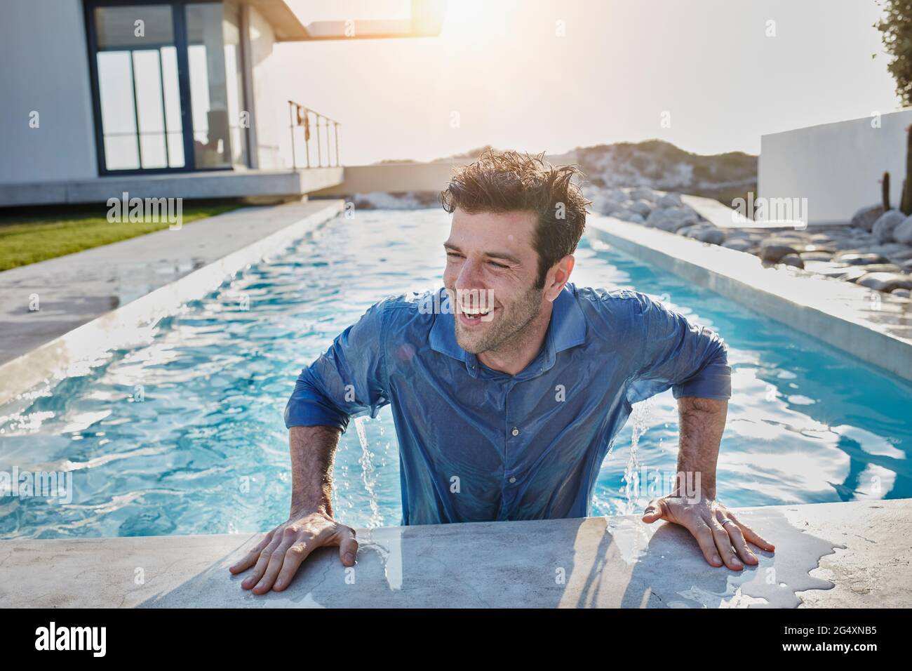 Cheerful man coming out of swimming pool while looking away Stock Photo