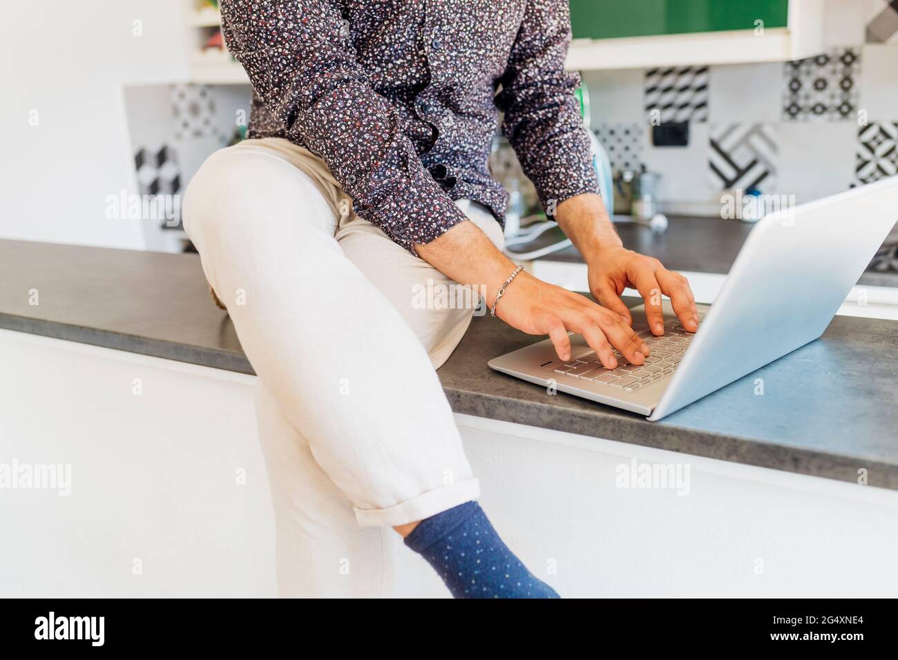 Man in casuals using laptop on kitchen island at home Stock Photo