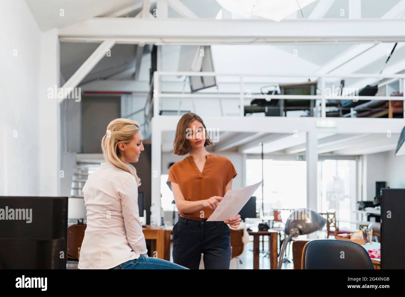 Female colleagues discussing over document in creative office Stock Photo